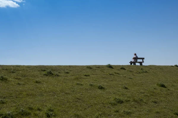 Mujer adulta se sienta en un banco disfrutando de la naturaleza — Foto de Stock