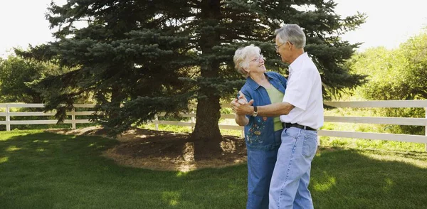 高齢者のカップルが公園で一緒に踊る — ストック写真