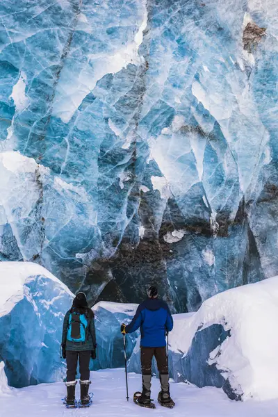 在科惠冰川的终点底部有几块倒塌的冰块 Snowshoers 对着蓝色的大冰墙进行检查 阿拉斯加 — 图库照片