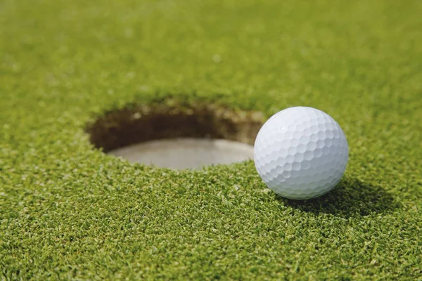 Bola de golfe perto de buraco — Fotografia de Stock