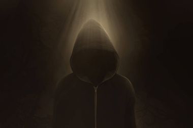  A dark and sinister figure in a hood against black. clipart