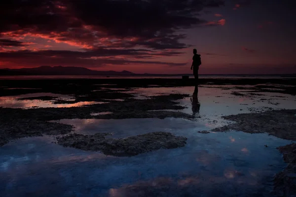 Die Silhouette eines Mannes am Strand bei Sonnenuntergang. — Stockfoto