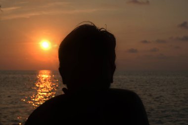 Gün batımı kumsalında eğlenen bir sürü insan.