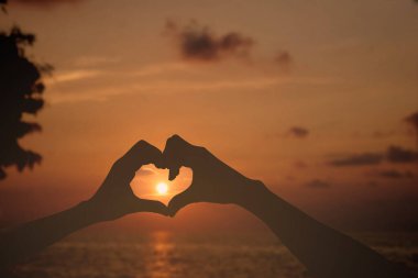 Gün batımı sahnesi, turuncu gökyüzü ile siluet el hareketi 