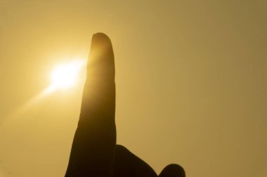 Gün batımı sahnesi, turuncu gökyüzü ile siluet el hareketi 