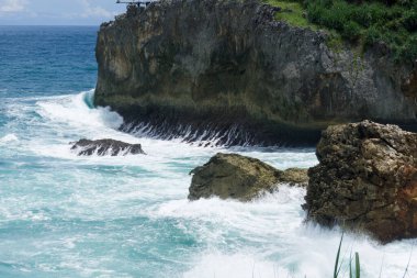 Dalgalar kayalıklara çarpıyor, yukarıdan görünüyor.