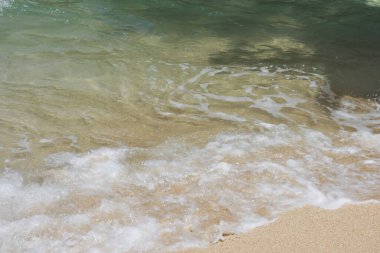 Güzel deniz ya da okyanus fırtınalı su dalgaları beyaz köpüklü ya da köpüklü güneşli bir günde kıyıya sıçrayan ve yuvarlanan 
