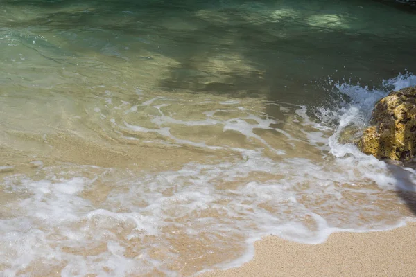 Beautiful waves of sea or ocean stormy water with white foam or froth splashing and rolling to shore on sunny day