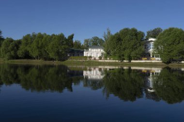 Binalar yakın göl güneşli sabahın erken saatlerinde ağaçlar arasında.