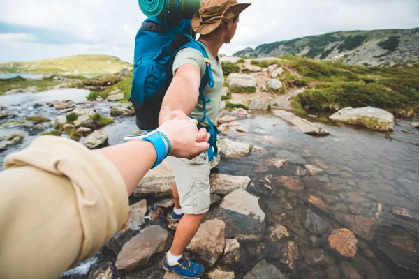 Man and woman  crossing a river on stones — Stock Photo, Image