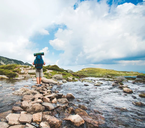 Hiker man with backpack crossing a river — Stock Photo, Image