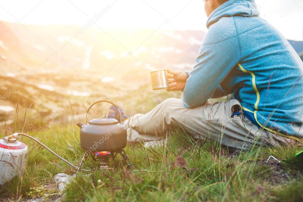 Young man drinking tea at the mountain