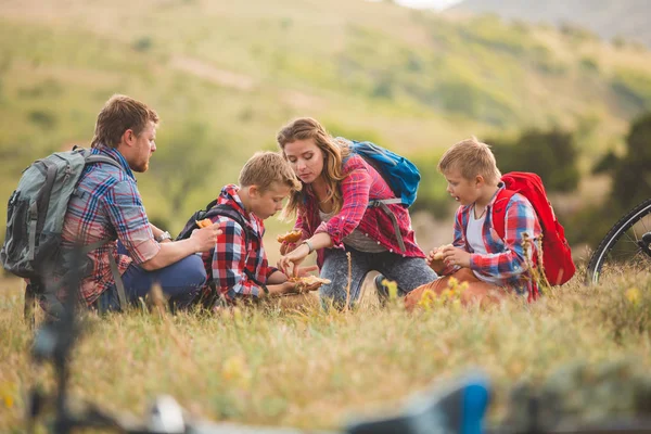 Family of four people eating fastfood in mountains — Stock Photo, Image