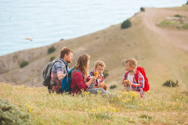 Família de quatro pessoas comendo fast food nas montanhas — Fotografia de Stock