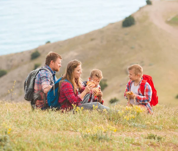Family of four people eating fastfood in mountains
