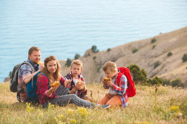 Familia de cuatro personas comiendo comida rápida en las montañas — Foto de Stock