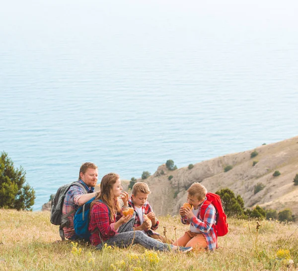 Family of four people eating fastfood in mountains — Stock Photo, Image