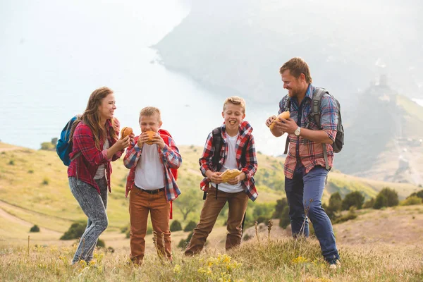 Familia de cuatro personas comiendo comida rápida en las montañas — Foto de Stock