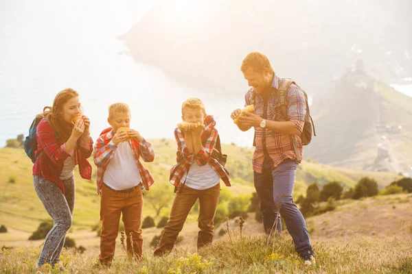 Familia de cuatro personas comiendo comida rápida en las montañas — Foto de Stock