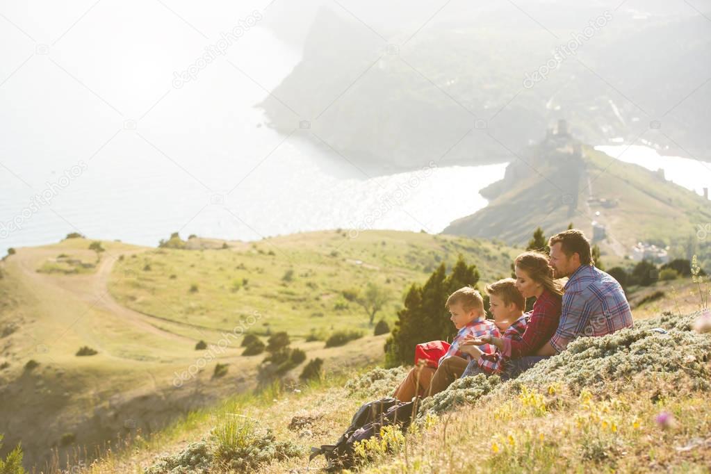 Family of four people looking to beautiful seascape in mountains