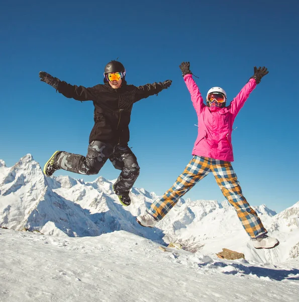 Feliz pareja de snowboarders saltando en las montañas alpinas — Foto de Stock