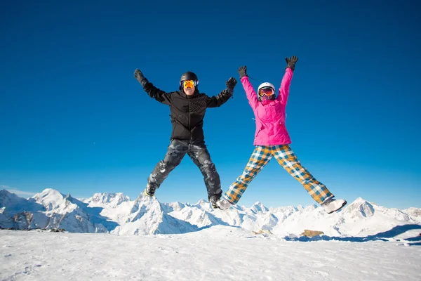Happy couple of snowboarders jumping in the alpine mountains — Stock Photo, Image
