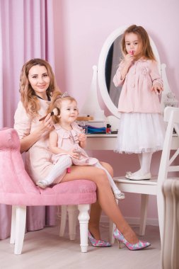 Anne ve iki kızı dudak makyaj yapıyor.