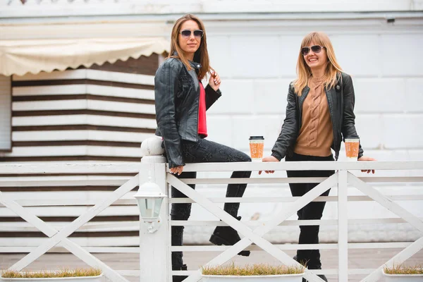 Ritratto di due belle ragazze con tazze di carta di caffè in mano . — Foto Stock