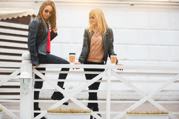 Retrato de duas belas namoradas com xícaras de papel de café nas mãos . — Fotografia de Stock