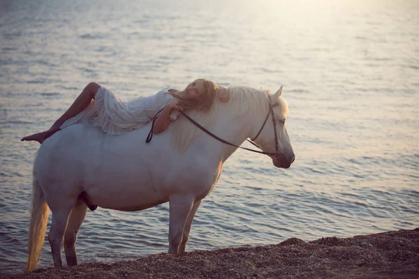 Девушка в белом платье с лошадью на пляже — стоковое фото