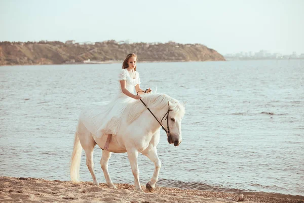 Dziewczyna w białej sukni z konia na plaży — Zdjęcie stockowe