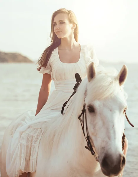 Девушка в белом платье с лошадью на пляже — стоковое фото