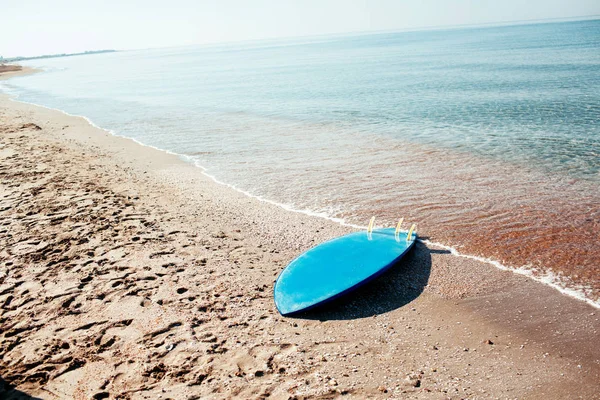 Surf board laying on the sand near the sea — Stock Photo, Image