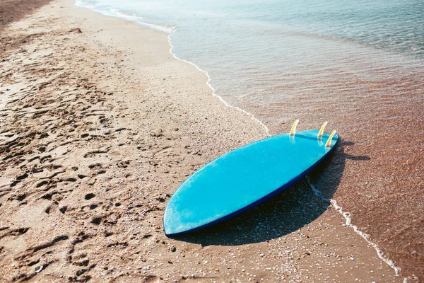 Surf board laying on the sand near the sea — Stock Photo, Image