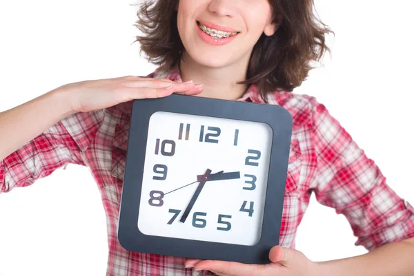 Chica con una camisa a cuadros con tirantes multicolores sosteniendo un reloj —  Fotos de Stock