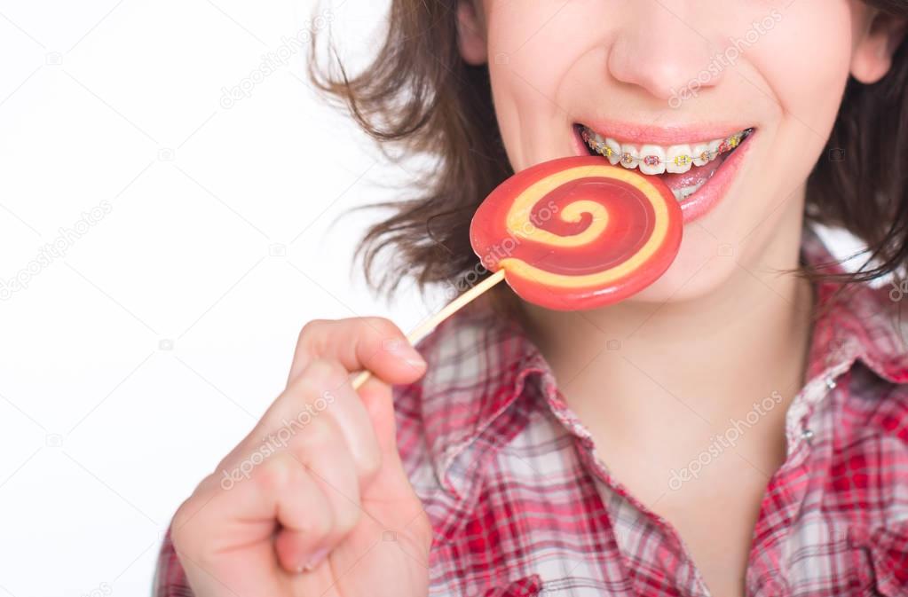 Close-up shot of girl with multicolored bracket systems and lollipop