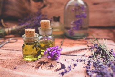Ahşap arka plan üzerinde taze çiçekler ile lavanta yağı.