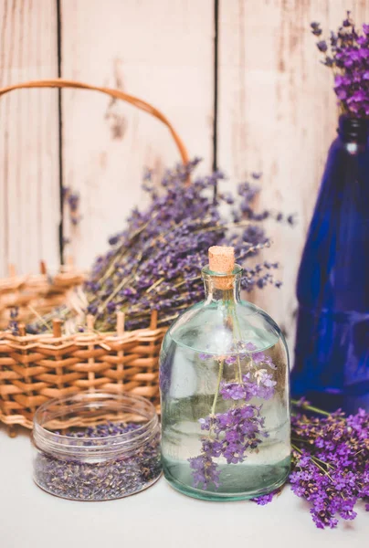 Olio di lavanda con fiori freschi su sfondo di legno . — Foto Stock