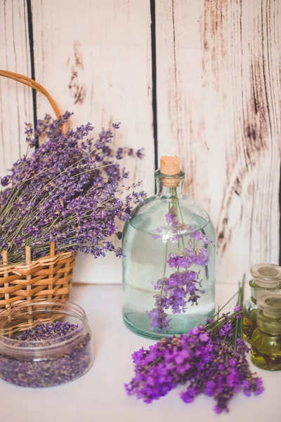 Aceite de lavanda con flores frescas sobre fondo de madera . — Foto de Stock