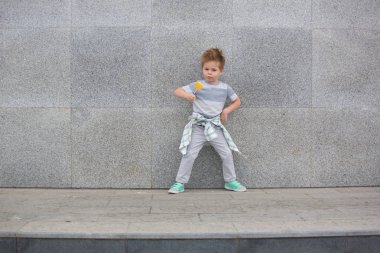 Moda çocuk gri duvarının yakınında