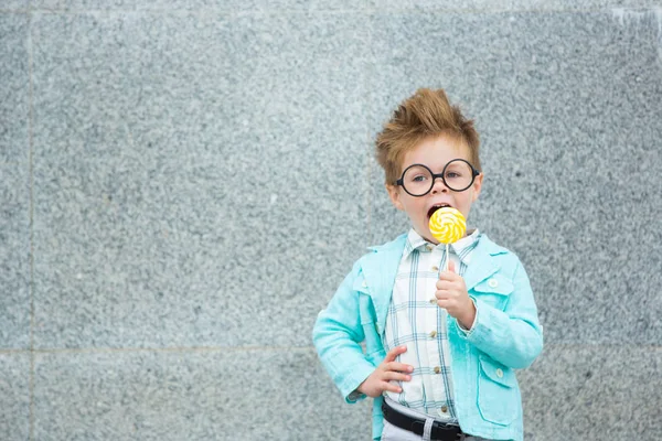 Criança de moda com pirulito perto da parede cinza — Fotografia de Stock