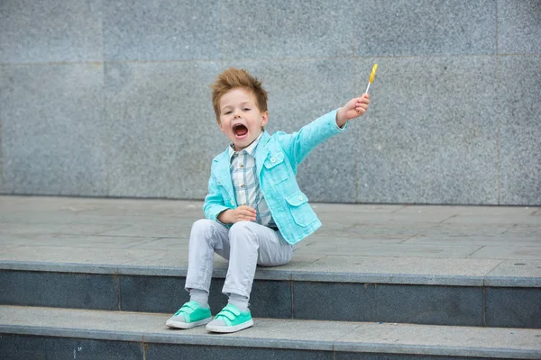 Criança de moda com pirulito perto da parede cinza — Fotografia de Stock