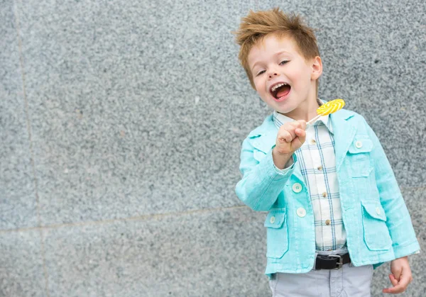 Fashion kid with lollipop near gray wall — Stock Photo, Image