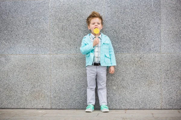 Bambino di moda con lecca-lecca vicino alla parete grigia — Foto Stock