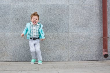 Moda çocuk gri duvara yakın poz