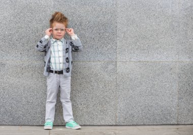 Gri duvarının yakınında gözlüklü moda çocuk