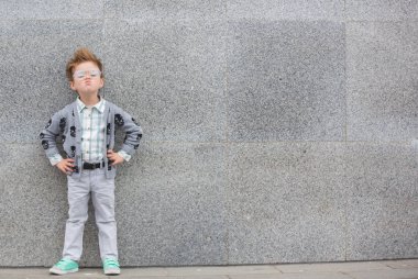 Gri duvarının yakınında gözlüklü moda çocuk