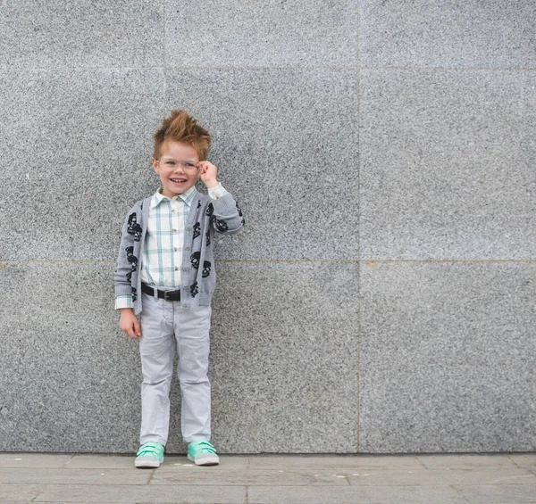 Fashion kid with glasses near gray wall — Stock Photo, Image