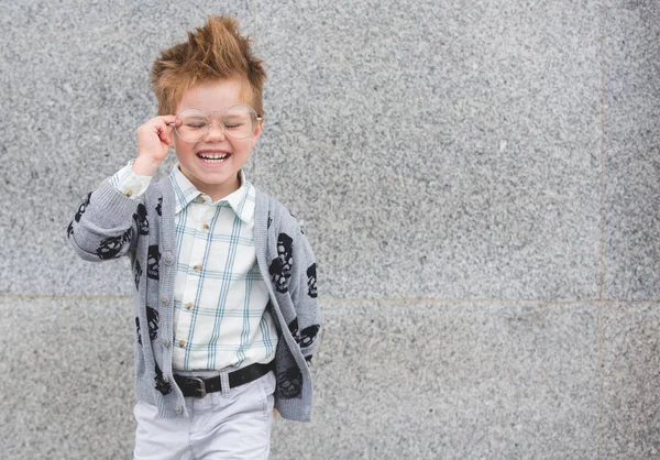 Enfant de mode avec des lunettes près du mur gris — Photo