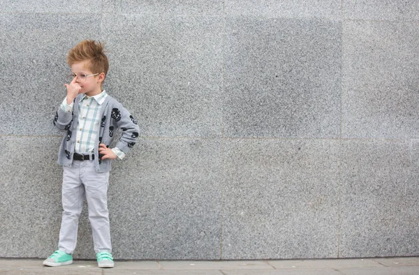 Bambino di moda con occhiali vicino alla parete grigia — Foto Stock